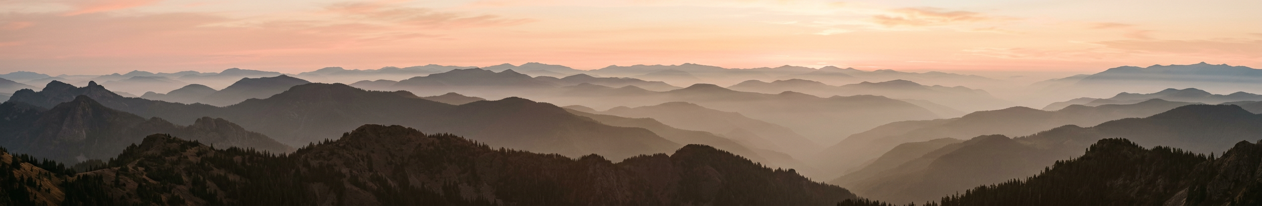 Layered mountain ridges fading into a peach sky, a generated image.